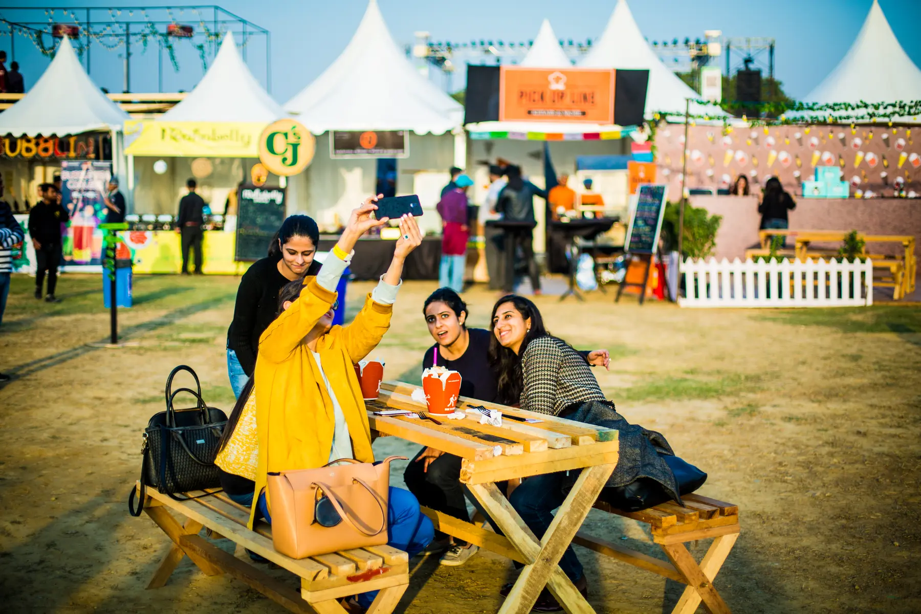 Friends taking a selfie at picnic benches between stalls